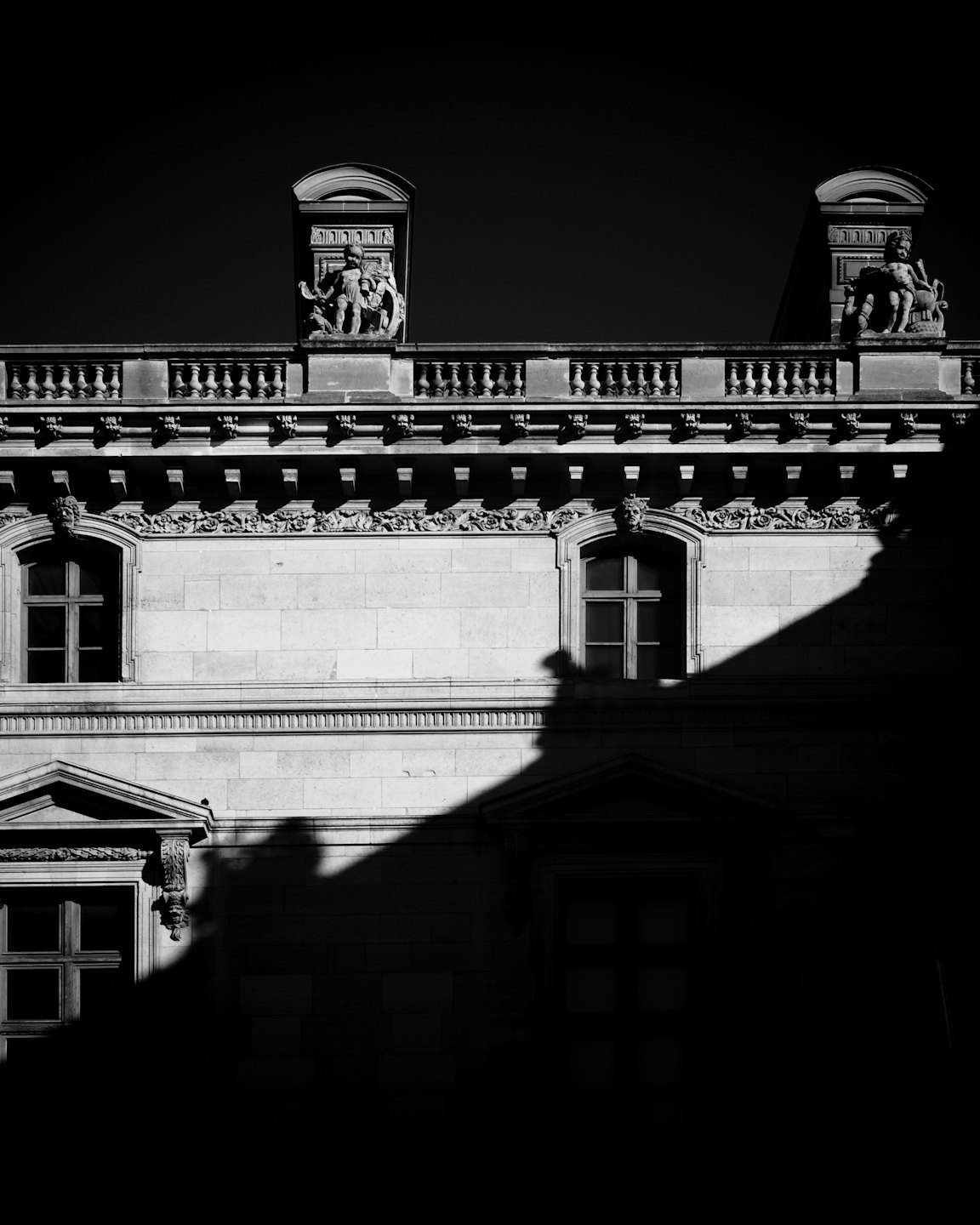 Facciata in pietra ornata con finestre ad arco e dettagli architettonici classici.