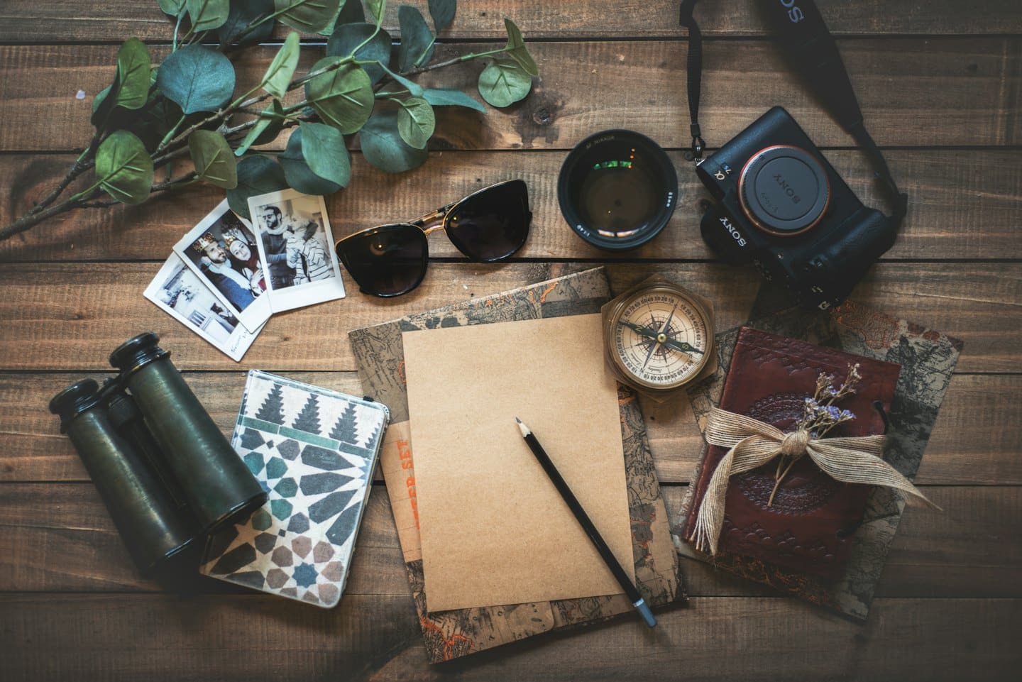 Oggetti da viaggio e per la fotografia disposti su un tavolo di legno.