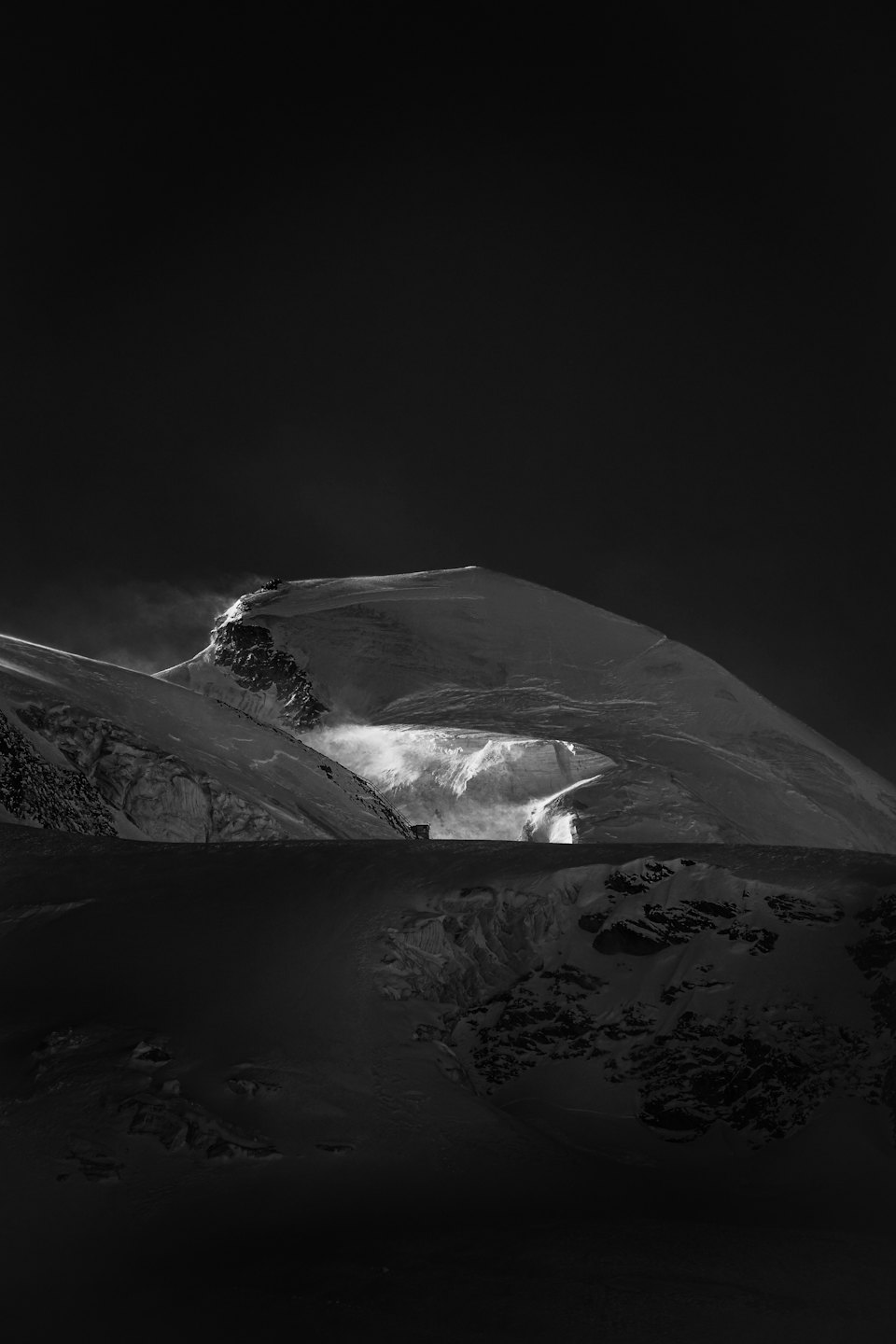 Cime innevate con neve che vola nel paesaggio.