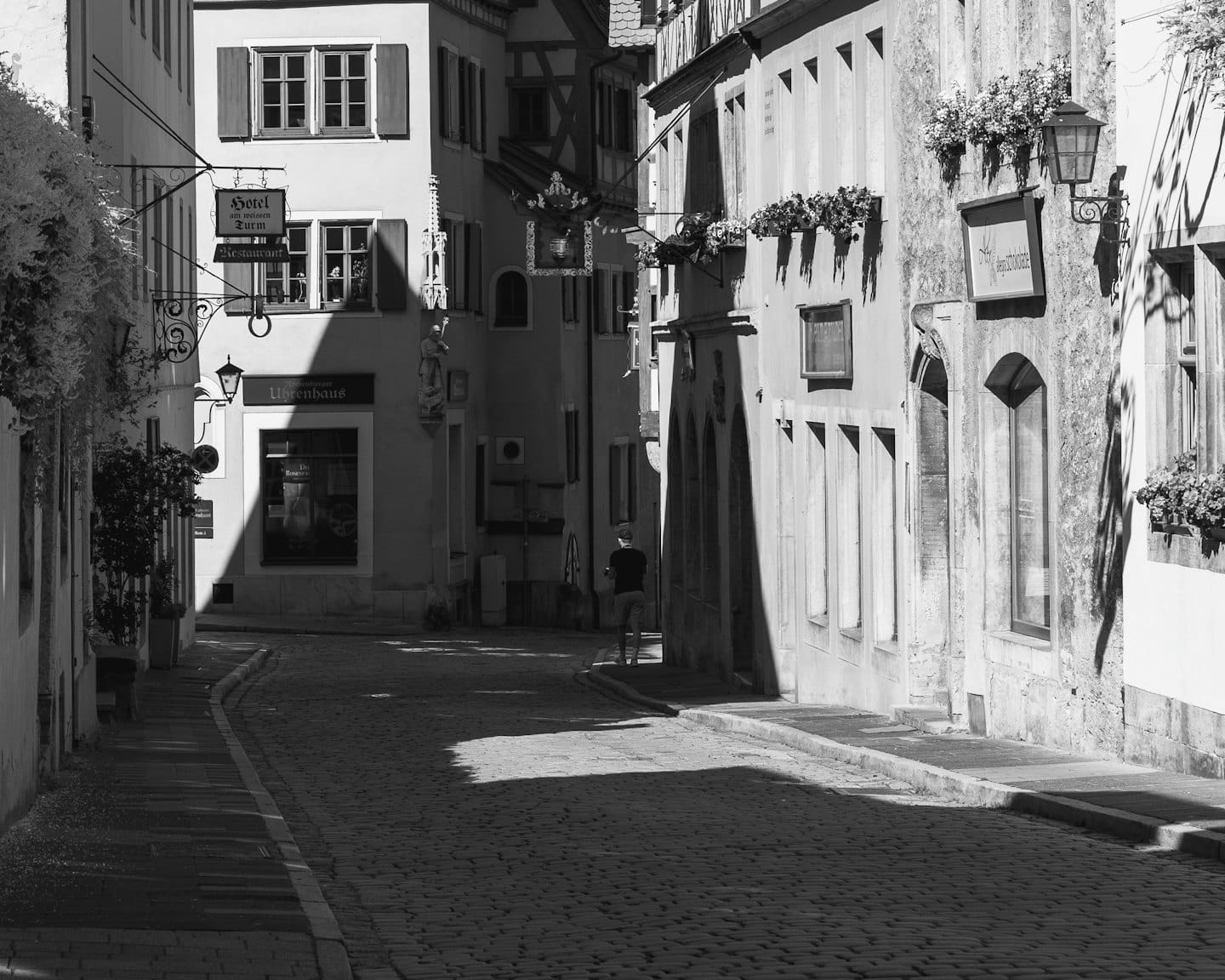 Strada acciottolata in un borgo storico con una persona che si allontana.